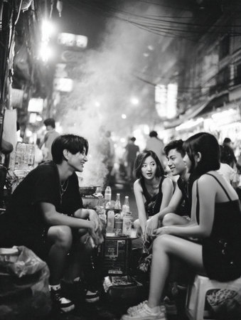 Friends gather to share laughs and street food at a bustling night market, surrounded by soft light and urban atmosphere during the evening hours.の素材