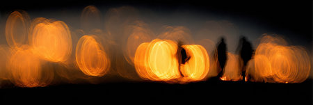 Figures stand in silhouette against warm, glowing lights during a tranquil evening, creating a peaceful ambiance that invites reflection.の素材