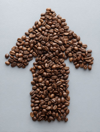 Coffee beans are creatively shaped into an upward arrow on a gray background, symbolizing energy, upliftment, and a passion for coffee culture.の素材