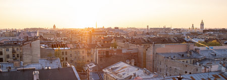 As the sun sets, warm light casts a golden hue over the rooftops of St Petersburg, illuminating the...