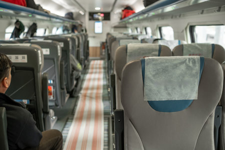 Seating inside a modern train with minimal passengers and a focus on the clean and spacious interior while traveling in the afternoon.の写真素材