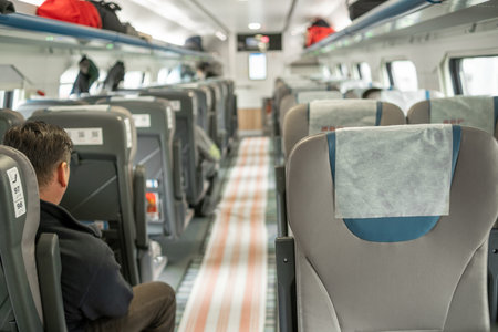 Passengers enjoy a serene journey on a train, with ample seating and soft natural light filtering through the windows.の写真素材