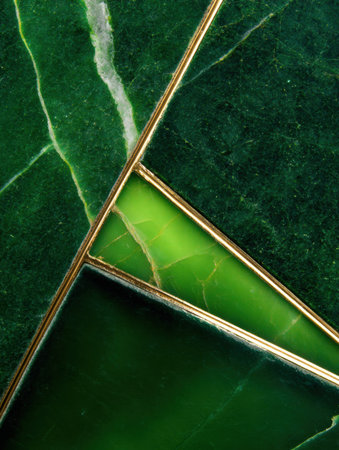 Close-up view of polished green marble tiles showing intricate patterns and shades with contrasting gold lines.の素材