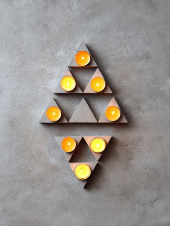 Seven tea lights are lit, nestled in triangular gray concrete holders.の素材