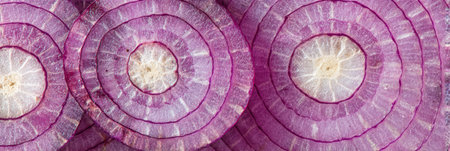 Sliced red onion bulbs stacked showing purple concentric rings, white centers, and texture details.の素材