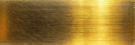 Close-up of a brushed gold metal surface showing light reflections and subtle texture variations.の素材