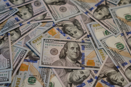 Money is spread out on a flat surface, highlighting the intricate designs and colors of various hundred dollar bills.の写真素材