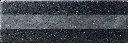 Close-up view of a textured block displaying a prominent gray stripe against a dark background with surface details.の素材