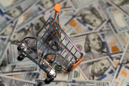 A small cart on a big money pile creatively connects shopping and finances.の写真素材