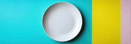 A clean white plate rests on a bright turquoise background, complemented by yellow and pink accents, creating a striking minimalist scene.の素材