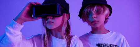 Two kids are exploring virtual reality using a headset in a vibrant and colorful space filled with playful lighting.の素材