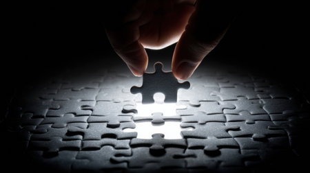 A man focuses intently as he places the final puzzle piece into its spot, symbolizing problem solving and achievement.の素材