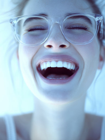 A young woman laughs brightly while wearing transparent glasses, capturing a moment of happiness and joy in a vibrant setting.の素材
