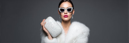 A sophisticated model holds a glowing glasses case, dressed in stylish attire, set against a minimalist backdrop, conveying luxury and elegance.の素材