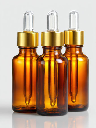 Three brown glass dropper bottles with gold caps are placed on a white surface, creating a clean and minimal pharmacy aesthetic look.の素材