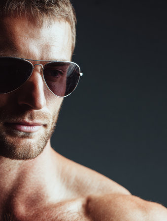 Male model exudes confidence while wearing aviator glasses, captured against a sleek dark gradient backdrop, amplifying his bold expression.の素材