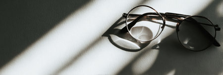 Glasses rest on a clean background, illustrating a captivating duality with light and shadow playing over the surface.の素材