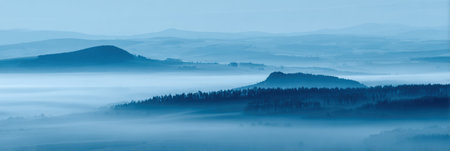 Soft morning mist blankets the rolling hills, enhancing the tranquil mood of the landscape at dawn.の素材