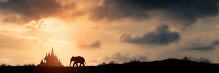 An elephant strolls peacefully near a traditional Thai temple as the sun rises, casting warm colors across the sky.の素材