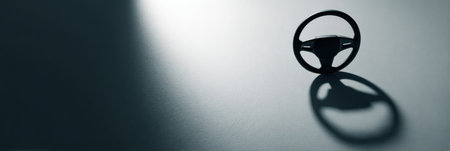 Steering wheel positioned on a metallic surface creates a striking shadow, highlighting the clean lines and smooth texture of the scene.の素材