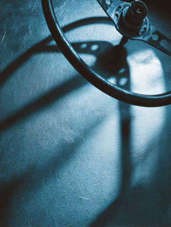 A steering wheel creates an intriguing shadow on a metallic surface, showcasing a clean automotive vibe and attention to detail.の素材