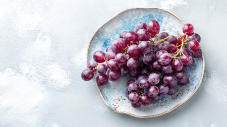 A ceramic plate holds a cluster of fresh grapes, showing rich colors and unique natural details in a simple presentation.の素材
