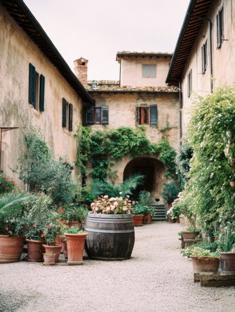 Rustic courtyard in Tuscany showcases a wooden barrel filled with wine, surrounded by flowering plants, creating a peaceful atmosphere.の素材