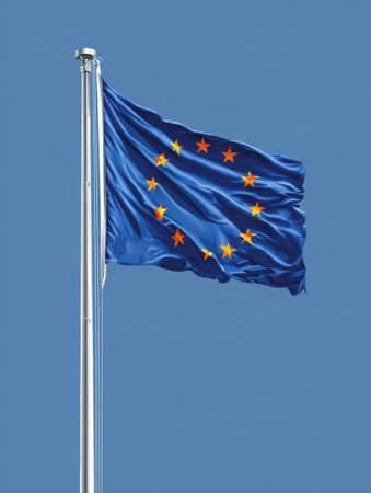 The European Union flag is displayed, fluttering in the wind against a bright blue sky, symbolizing unity among member nations.の素材