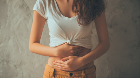 A woman holds her abdomen, indicating discomfort associated with urinary tract infection and the challenges of overactive bladder.の素材