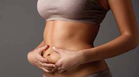 A woman demonstrates how to grab belly fat during a diet consultation in a high-detail studio environment focused on health and fitness.の素材