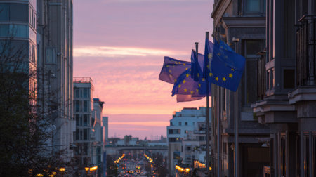 European Union flags wave gently in a city as the sunset casts soft light, celebrating Europe Day in a vibrant urban setting.の素材