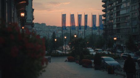 European Union flags fly gracefully as the sun sets in a city, illuminating the soft evening sky and nearby urban scenery.の素材