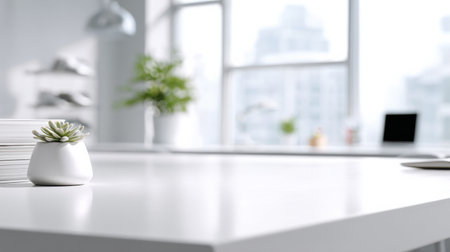 Modern office with a white desk, small plant, and paper stacks, filled with natural light from large windows.の素材