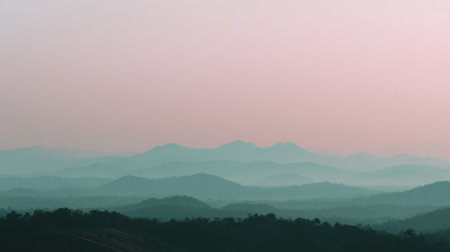 Mountains rise in layers against a pastel sky during the evening, with empty space for text below the horizon.の素材