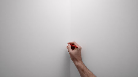 Single man using a small brush to finish painting where two walls meet in a minimal indoor space focused on details.の素材