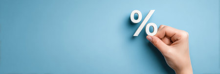 A hand grips a percent symbol on a light blue backdrop, illustrating themes like business, finance, and discount offers in various transactions.の素材