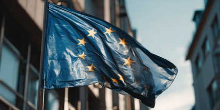 Flag of the European Union flutters in the breeze outside a contemporary parliament building on a bright, sunny day marking Europe day and elections.の素材