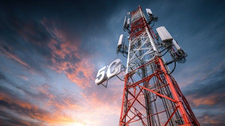 A communication tower equipped with 5G antennas stands tall against a colorful sunset, broadcasting mobile signals for fast internet access.の素材