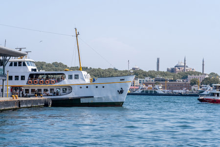 Ferry docked along the Bosphorus with cityscape backdrop in Istanbul, featuring historical architecture and calm waters under clear skiesのeditorial素材