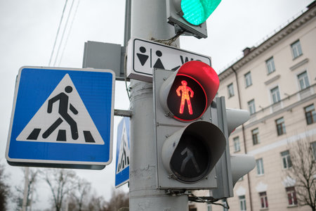 Pedestrian signals indicate when to walk or wait at a street crossing in a city as vehicles are stopped by traffic lights.の写真素材