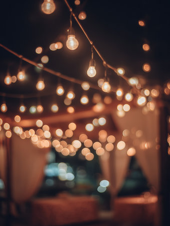 Soft glowing lights hang in a cozy outdoor setting, creating a warm atmosphere for people enjoying an evening festival under the sky.の素材