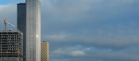 Construction Activity at a Tall Building Site Under a Cloudy Sky in an Urban Setting