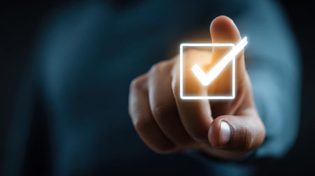 Hand is positioned above a bright confirm transaction button while engaging in an online payment action in a low light environment.の素材