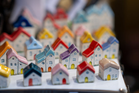 Miniature ceramic houses with colorful roofs are arranged in a display, featuring intricate details and a blurred background for depth