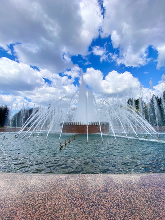 Beautiful Fountain With Cascading Water Streams Against a Blue Sky in a Public Park During the Afternoon