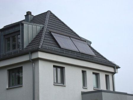 A modern residential house with solar panels on its sloped roof showcases energy-efficient technology and an eco-friendly approach to power use.の写真素材