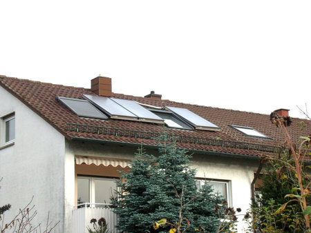 Solar thermal collectors installed on a townhouse roof provide hot water and improve energy efficiency, showcasing the use of renewable energy.の写真素材
