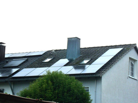 Solar panels installed on the roof of a large residential house provide part of its energy needs, reducing dependence on the electrical grid.の写真素材