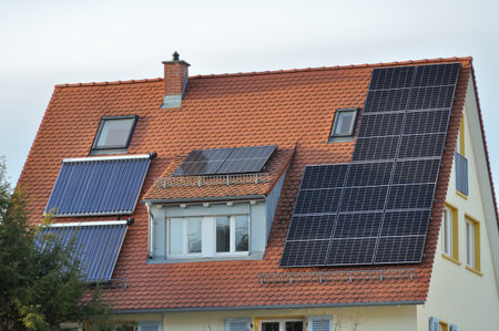 House roof with photovoltaic panels and vacuum solar collectors. A combined system for electricity and hot water production.の写真素材
