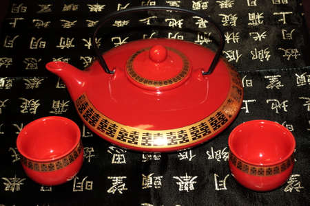 Teapot and two cops of tea with tea on the front (focus on cups)On a table cloth with hieroglyphs.の写真素材